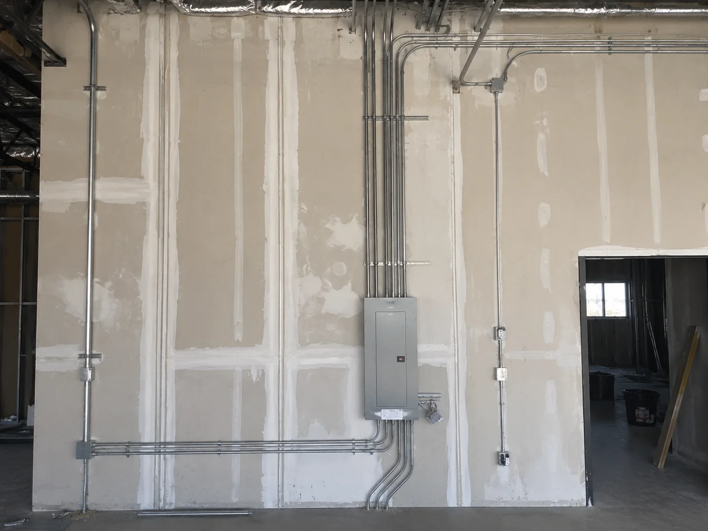 Neatly arranged electrical conduit inside a framed commercial wall