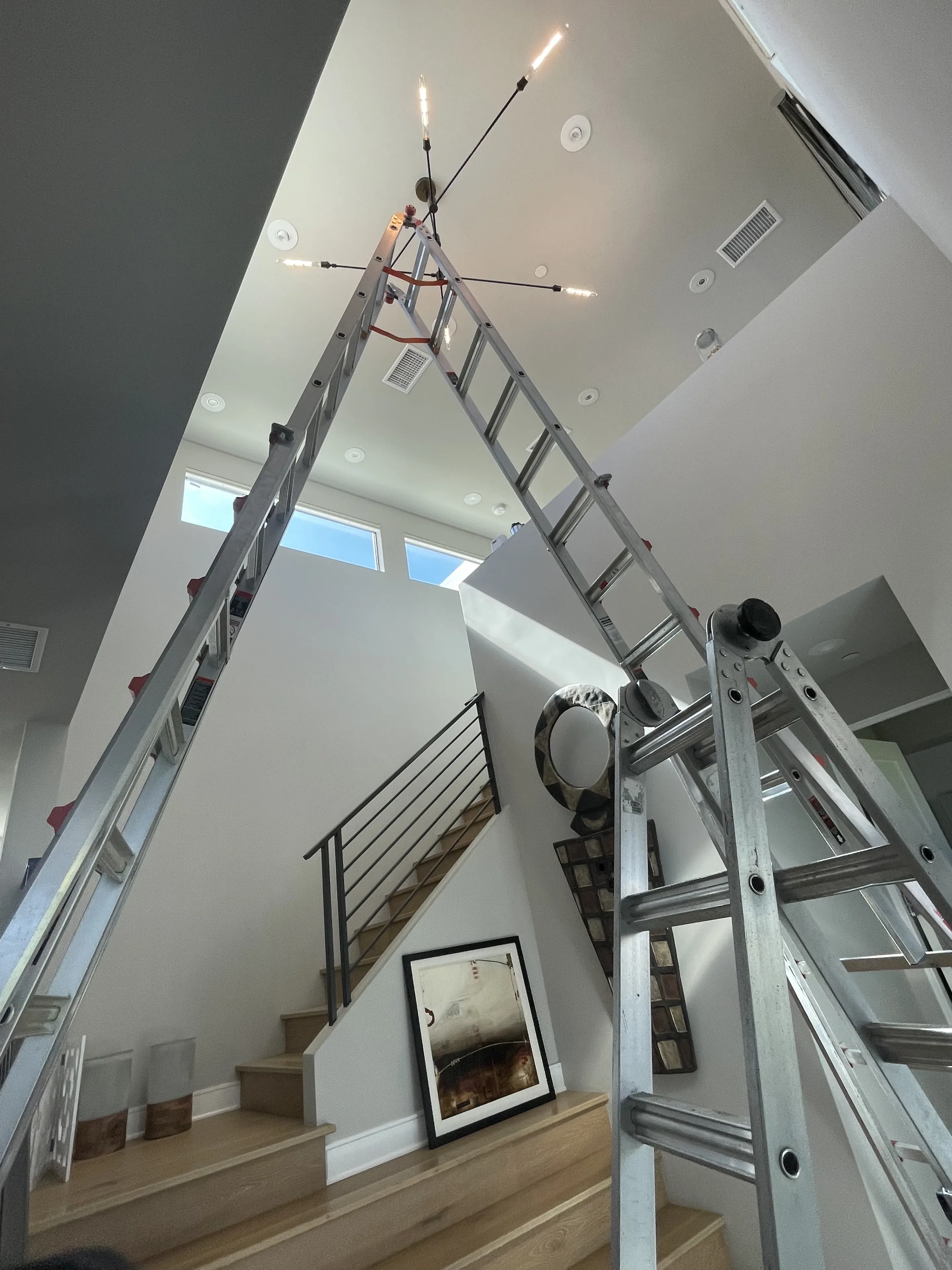 Two-story chandelier installation in a finished residential interior